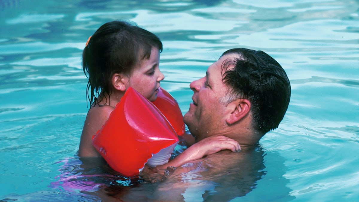 Father and Daughter in a Pool. A 10 year-old Caucasian girl with her father in a swimming pool. She was diagnosed at age three with a form of Acute Lymphoblastic Leukemia (ALL) that did not respond to therapy. She is presently in long-term remission after an experimental bone marrow transplant was performed. She now suffers from chronic GVH (Graft Versus Host Disease) which is rare.